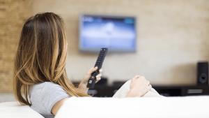 a woman holding a remote control in front of a television at Hotel Aguila in Guadalajara