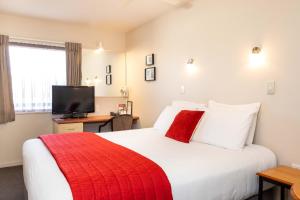 - une chambre avec un grand lit et une couverture rouge dans l'établissement Bella Vista Motel Napier, à Napier