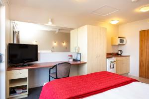 a room with a bed and a desk with a television at Bella Vista Motel Napier in Napier