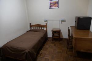 a small bedroom with a bed and a flat screen tv at Hotel Julia in Uyuni