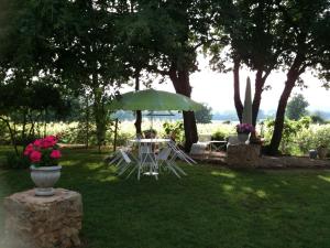 a table and chairs under an umbrella in the grass at Chambre d'Hôte Couguiolet - avec piscine in Foissac