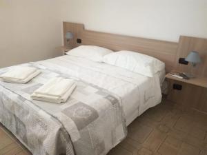 a large white bed with two white towels on it at La casa di Mela in Leverano