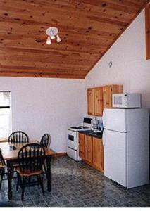 Il comprend une cuisine équipée d'un réfrigérateur blanc, d'une table et de chaises. dans l'établissement Chisholms of Troy Coastal Cottages, à Port Hawkesbury