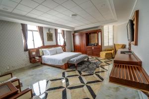Duc Long Gia Lai Hotels & Apartment في بلاي كو: غرفة نوم بسرير وطاولة واريكة