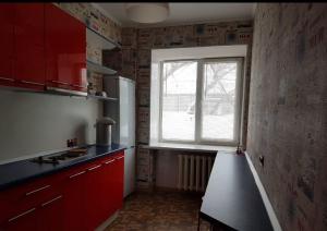 a kitchen with red cabinets and a window at Hostel 888 У Вокзала in Novosibirsk