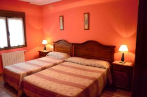 a bedroom with two beds with orange walls and two lamps at Labeondo in Muskiz