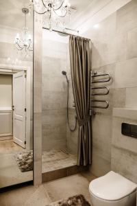a bathroom with a shower with a toilet and a chandelier at Kranto apartamentai in Panevėžys