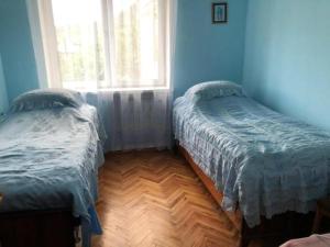 2 łóżka w niebieskim pokoju z oknem w obiekcie S&S house w mieście Khashtʼarrak