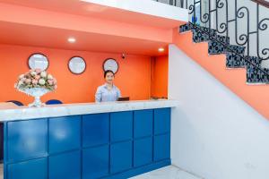 a man standing behind a counter in a room with orange walls at The Poppy Villa & Hotel in Hanoi