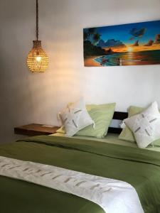 een slaapkamer met een bed met groene lakens en kussens bij Cape Rose2 in Gili Trawangan