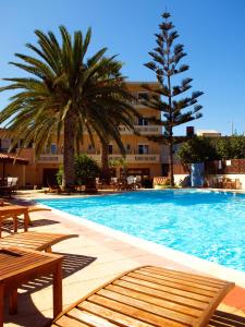 a swimming pool with two palm trees and a building at Kissamos Hotel in Kissamos