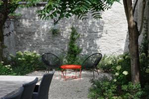 a red table and two chairs and a tree at House Forelle Gent in Ghent