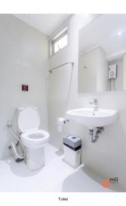 a white bathroom with a toilet and a sink at Pho Place in Bangkok