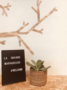 a sign on a table next to a plant at La Grande Maraudeuse in Theux