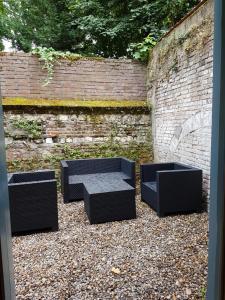 three black benches sitting in front of a brick wall at Charmant studio au coeur de St Leu hyper centre in Amiens
