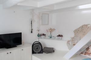 a living room with a tv and a fan at moonhouse in Skiathos