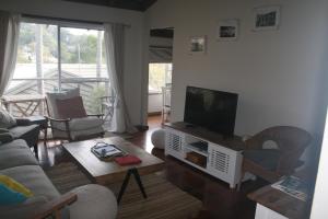 a living room with a couch and a tv at The Beach Hut Avoca Beach NSW in Avoca Beach