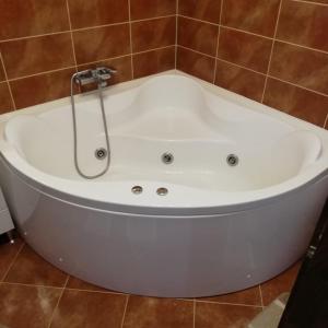 a white bath tub with a shower in a bathroom at Halasto Pension in Praid