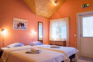 two beds in a room with orange walls at Herranniemi Guesthouse in Vuonislahti