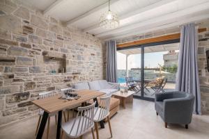 een woonkamer met een stenen muur en een tafel en stoelen bij EL.MA.RA. Luxury Villas in Kókkinos Pírgos