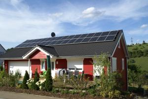 une maison rouge avec des panneaux solaires sur le toit dans l'établissement Heid-Blick, à Gomadingen