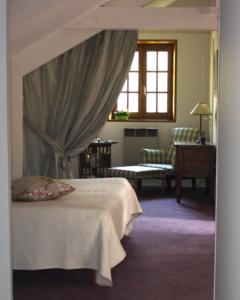 een slaapkamer met een bed, een stoel en een raam bij La rabouillere in Contres