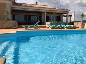 a swimming pool with chairs and a house at Casal das Oliveiras in Setúbal