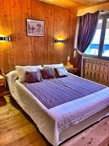 a bedroom with a large bed with wooden walls at Chez Marion in Notre-Dame-de-Bellecombe