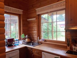 a kitchen with a sink and two windows in a log cabin at Коттедж в Финляндии (Тохмаярви) in Tohmajärvi