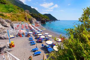 a beach with a bunch of chairs and umbrellas at Grand Hotel Pianeta Maratea Resort in Maratea