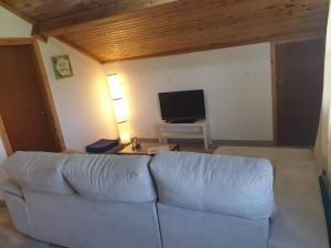 a living room with a white couch and a television at Quinta do Calvário in Lajes das Flores