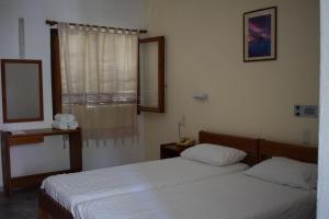 een slaapkamer met 2 bedden, een spiegel en een raam bij Porto Galini in Agia Galini