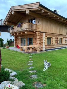 a log cabin with a dog sitting in the grass at Chalet Karin in Hochfilzen