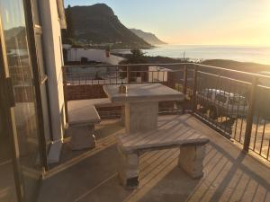 a picnic table on a balcony with a view of the ocean at Ollava Guesthouse in Simonʼs Town