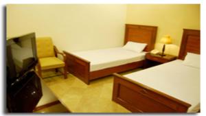 een slaapkamer met een bed, een stoel en een televisie bij Hotel Johar View in Lahore