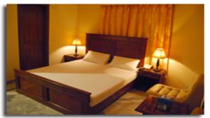 a bedroom with a bed and a chair and two lamps at Hotel Johar View in Lahore