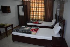 two beds in a room with a table and a mirror at Hotel Kashmir Inn in Rawalpindi
