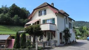a white house with a balcony on a street at Bahnhöfli Faulensee in Faulensee