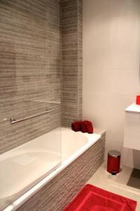 une baignoire dans une salle de bain avec un tapis rouge dans l'établissement PENTHOUSE OASIS BEACH, à Playas de Orihuela 16 autres photos
