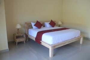 um quarto com uma cama grande com lençóis brancos e almofadas vermelhas em Dayuh Homestay em Amed