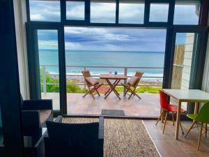 Habitación con mesa, sillas y vistas al océano. en Captain Sunshine Guest House, en Jongensfontein