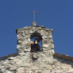 una persona che scatta una foto di una croce sulla cima di una torre di Maison Marthe a Coursegoules