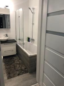 een badkamer met een ligbad en een wastafel bij Apartament Winorośli in Warschau