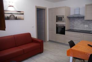 un soggiorno con divano rosso e una cucina di casa mariolu 2 bilocale a Cala Gonone