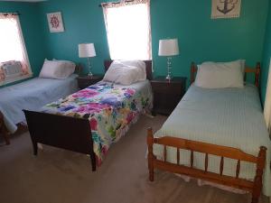two beds in a room with green walls at Thompson House Cape Cod in South Yarmouth