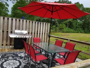 a table and chairs with a red umbrella on a deck at Thompson House Cape Cod in South Yarmouth