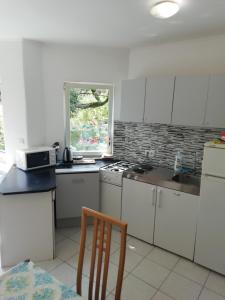a kitchen with white appliances and a table and a chair at Apartments Bosket in Kastav