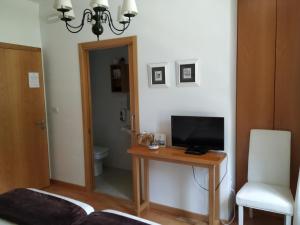 a room with a couch, chair and a television at Hotel Pazo de Berbetoros in Portomarin