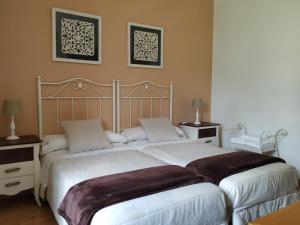a hotel room with two beds and two lamps at Hotel Pazo de Berbetoros in Portomarin