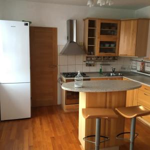 uma cozinha com um frigorífico branco e um balcão com bancos em Apartment Tekeľova 95m2 em Presov